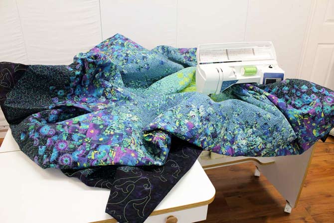 The entire quilt is supported on a small work surface.