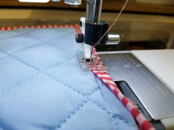 The needle is in the down position when I stop to reposition the binding, preventing a large stitch caused by movement of the project