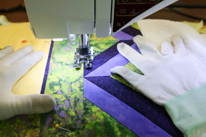 Using quilting gloves to help manipulate the quilt when stitching in the ditch.