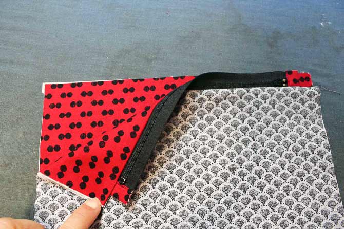 The unstitched edge of the zipper tape is lined up with the edge of the second outer fabric piece. Lay the other piece of lining on top of these pieces with rights sides together.
