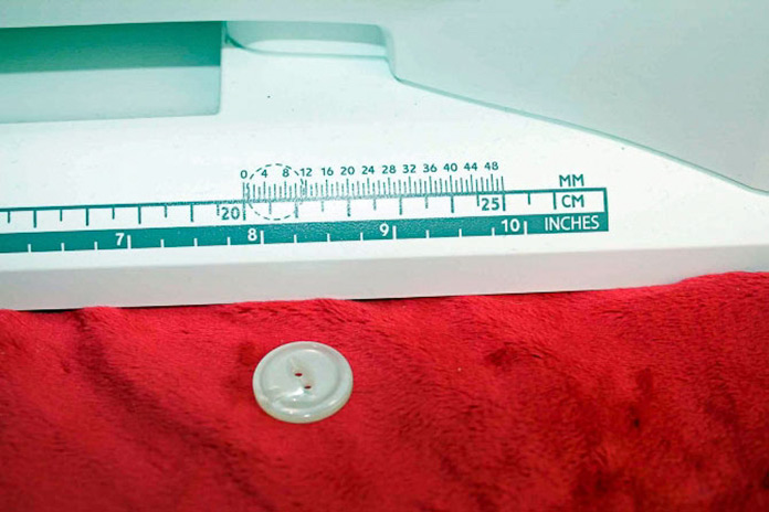 I have to 'tell' the Opal 690Q how large a button hole I want. A handy measuring device in millimeters is on the front of the sewing machine. Just lay your button on top of the guide and you'll see how big the buttonhole needs to be.