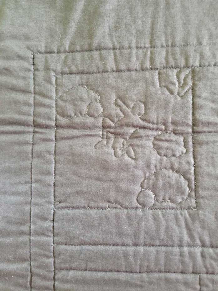 The back of the wallhanging shows one block with some free motion quilting