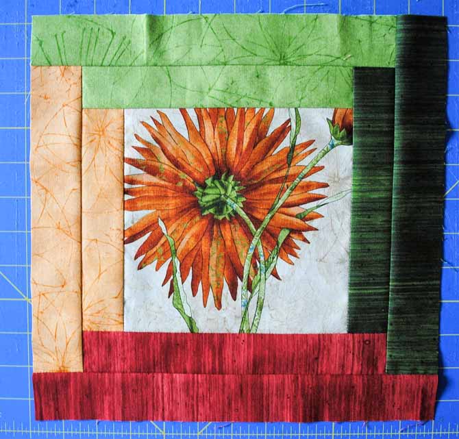 The finished twelve inch log cabin block made with the focus fabric, and red, lime green, dark green and orange Euphoria fabrics