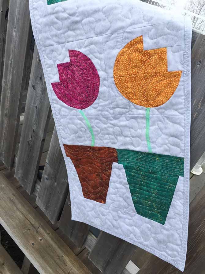 Quilted wall hanging with four tulips each in a flower pot. Northcott Artisan Spirit Shimmer Echoes.