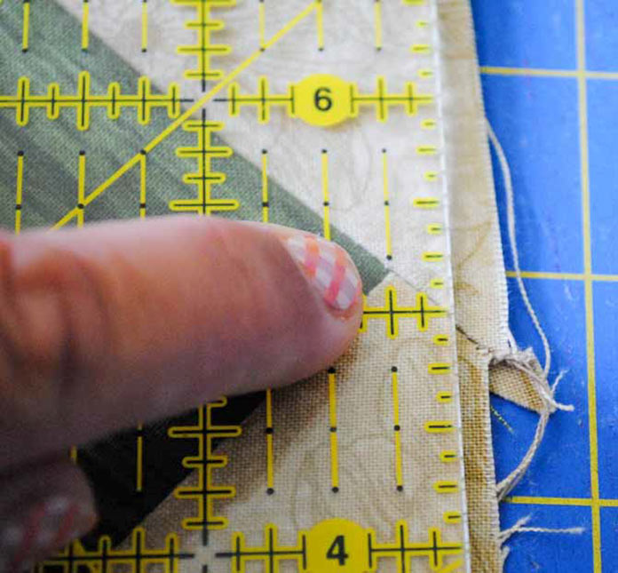 Lining up the rotary cutting ruler ¼” away from the points of the squares