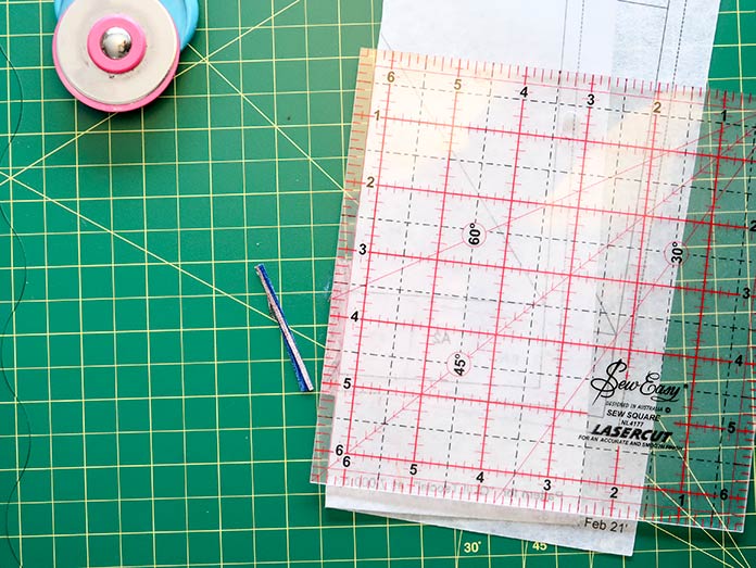  Fold the quilt block foundation sheet over for better access when trimming the fabrics to ¼". Gütermann threads, UNIQUE Dye Catcher and StitchnSew sheets, UNIQUE cutting mat.