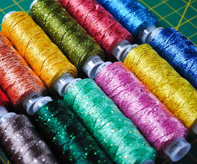 A rainbow of Dazzle threads from WonderFil are arranged on a cutting board.