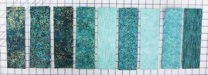 The 2½" x 8½" strips are cut from nine different Artisan Spirit Shimmer and Echoes fabrics in the Peacock colorway.