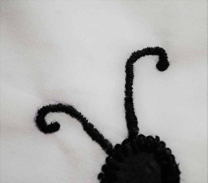 A closeup photo of the Brother NQ900 zigzag stitch used to embroider the antennae on the butterfly.