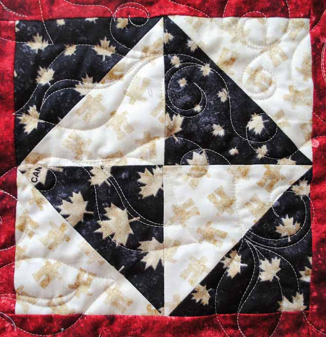 A close up of the leaf design machine quilted on the tablerunner using WonderFil's Master Quilter thread.