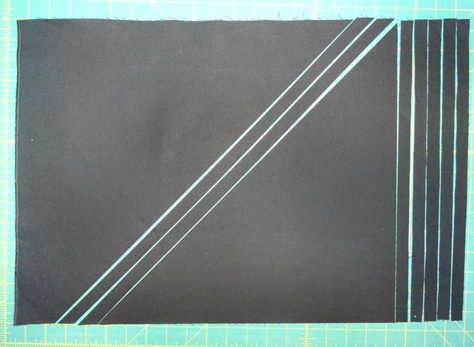 A rectangle of black fabric showing ⅝” strips cut on the diagonal and on the straight of grain.