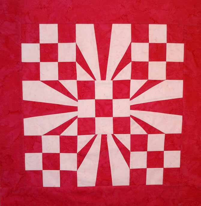 A red and white quilt top made of 5 nine patch blocks and 4 foundation piecing blocks. The 9 block quilt has a 3" red border. WonderFil DecoBob Prewound Bobbins.