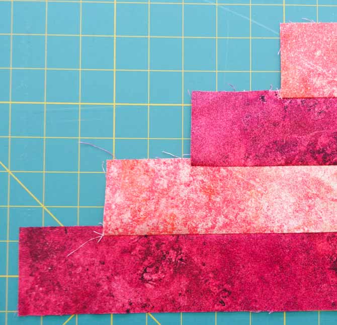 Four strips of fabric which are all the same width are sewn together in a step-wise fashion to reduce fabric waste when cutting the triangles.