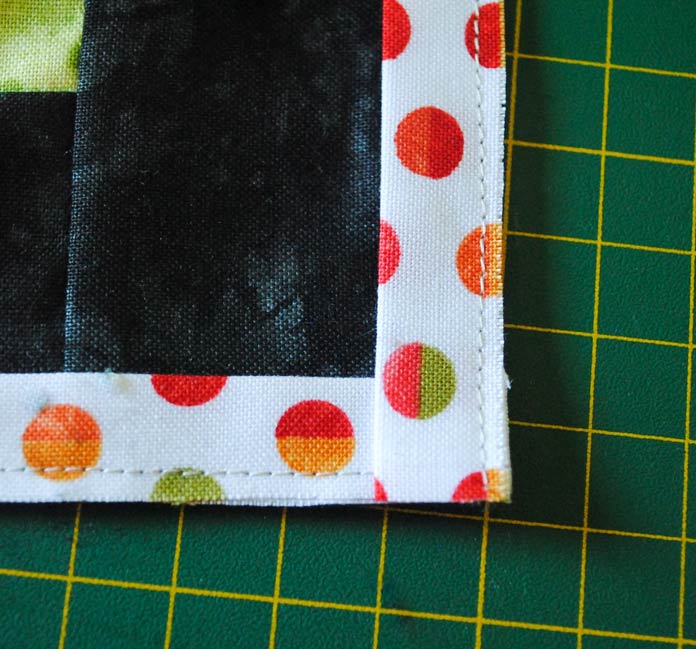 The flange accent strips are overlapped on the corners of the quilt made with the Full Bloom fabric from Northcott.