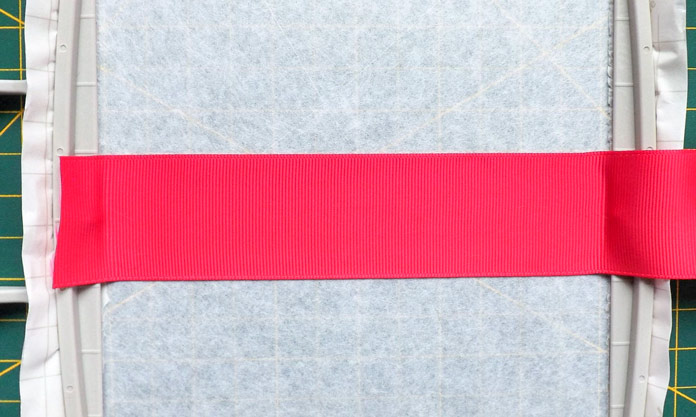 The first ribbon is centered across the Dreamweaver XE hoop and stuck to the stabilizer. A tutorial on how to make quilt labels using machine embroidery and ribbons using the Brother Dreamweaver XE