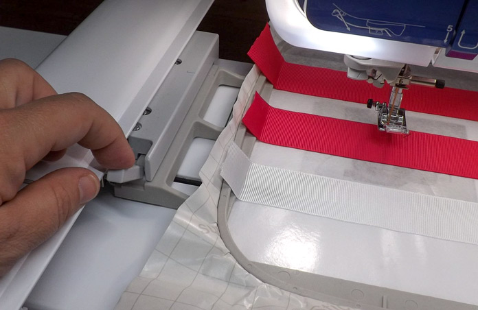 The embroidery hoop with stabilizer and ribbons is locked into the carriage of the Dreamweaver XE. A tutorial on how to make quilt labels using machine embroidery and ribbons using the Brother Dreamweaver XE