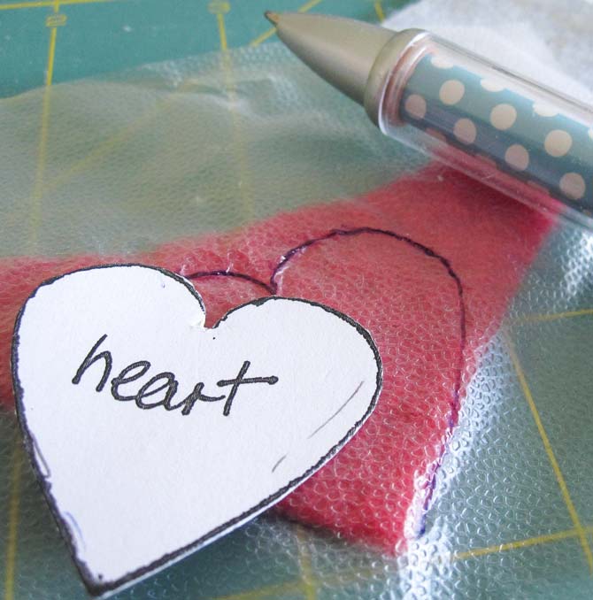 Tracing the heart shape on the food wrap over the red felt wool. WonderFil Specialty Threads.