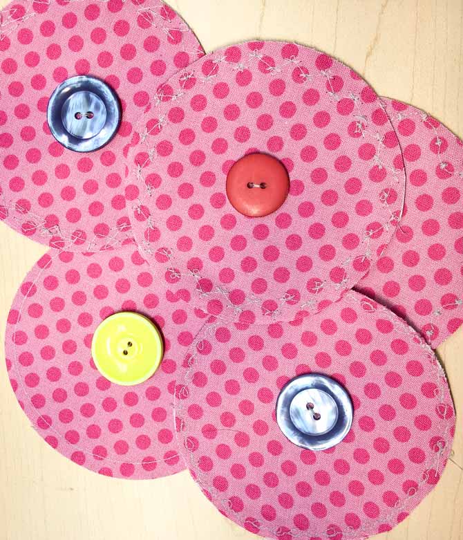 The Urban Elementz pink fabric circles are fused together so their right sides are out and a button stitched in the middle of each circle.