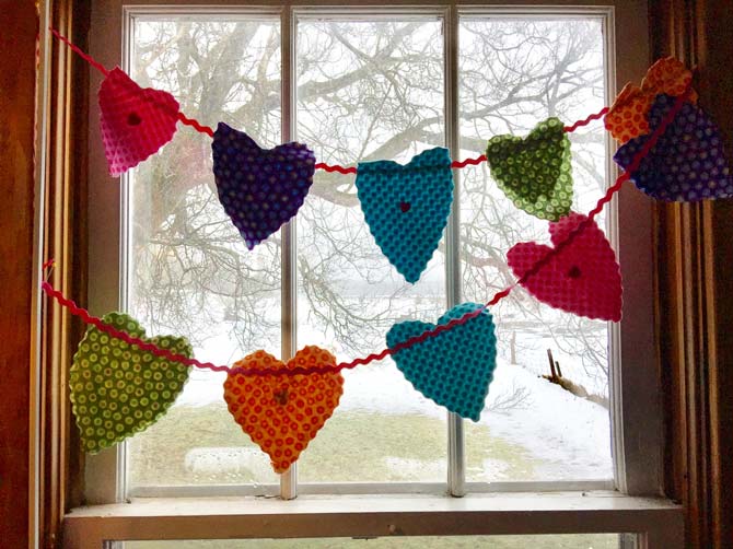 Fabric heart banner of many colors across a window.