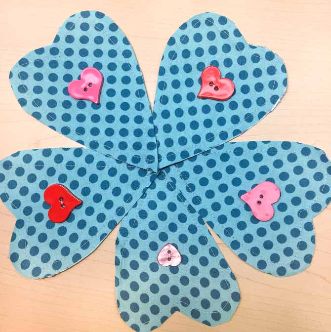 Five fabric heart shapes are made with Northcott's Urban Elementz fabrics and a heart button is sewn to the middle of each shape.