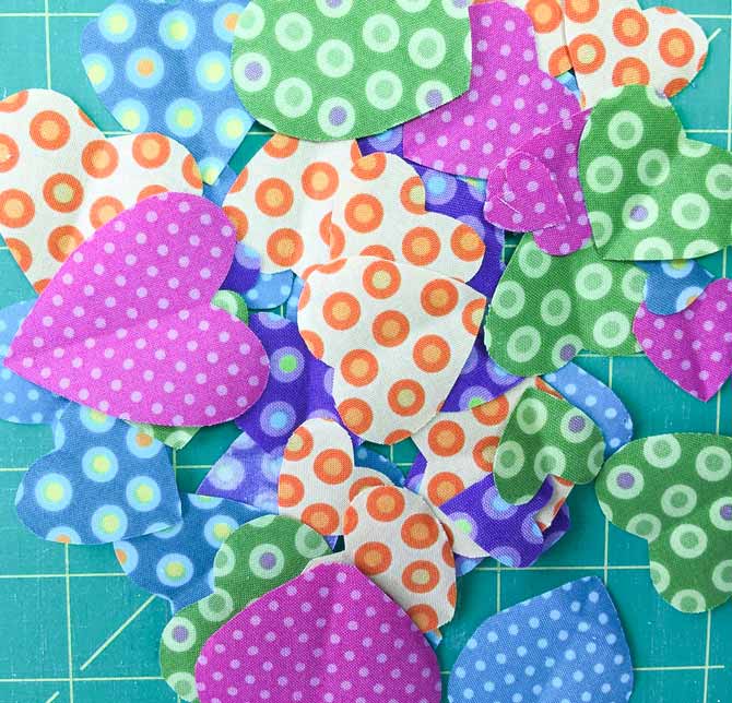 Various fabric hearts from different print fabrics on table.