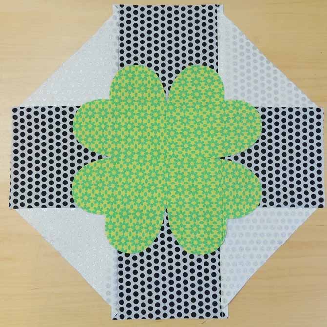 The clover leaf is placed on the center of the table topper so that the centers of the hearts are lined up with the triangles on the sides.