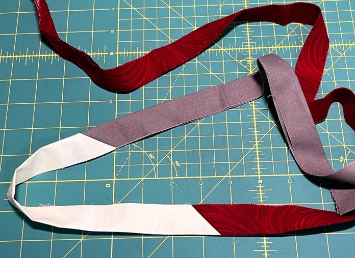 Leftover binding strip are sewn together to create bindings for scrap quilts.