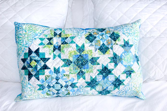 A decorative cushion made of quilt blocks from the Spectrum QAL bed runner.