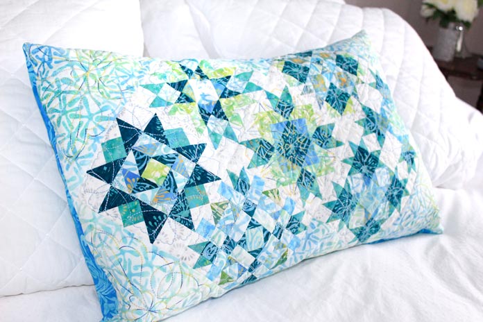 A decorative cushion made of quilt blocks from the Spectrum QAL bed runner.