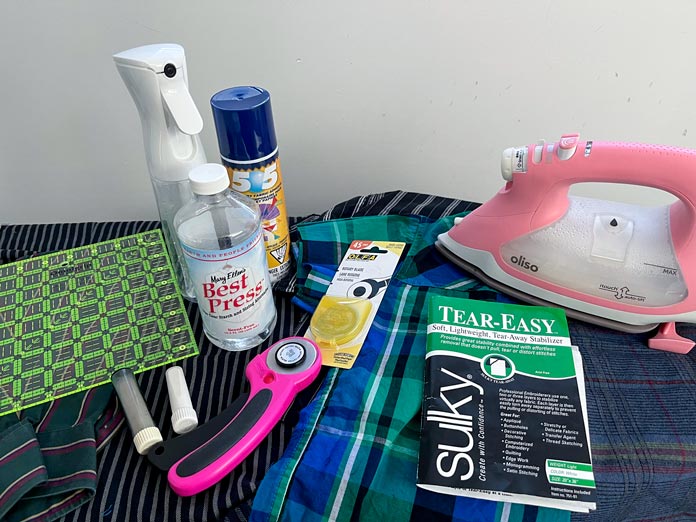 OMNIGRIP Ruler 8½" x 8½", OLFA 45 mm Ergonomic Rotary Cutter, OLFA Endurance Rotary Blades, Sulky Tear-Easy Stabilizer, Odif 505 Adhesive Fabric Spray, OLISO PRO TG1600 Pro Plus Smart Iron, Mary Ellen’s Best Press, Best Press Spray and Misting Bottle and the shirt fabric 