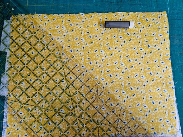A quilter’s ruler and a chalk marking tool on yellow fabric