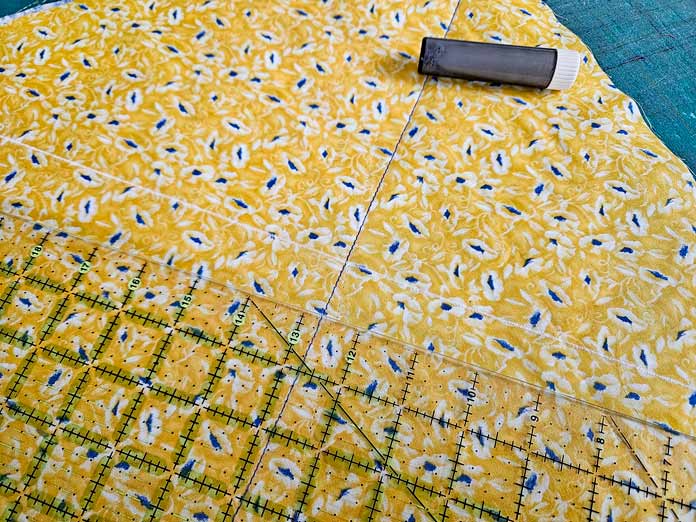 A quilter’s ruler and a chalk marking tool on yellow fabric; Husqvarna VIKING DESIGNER EPIC 3