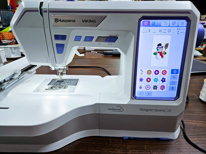 A white sewing and embroidery machine with a cute snowman embroidery showing on the computer screen; Husqvarna VIKING Designer Quartz 29, mySewnet Machine Embroidery Software, mySewnet Library, Husqvarna VIKING Tear-a-Way Light Stabilizer 15 Inches x 25 Yards