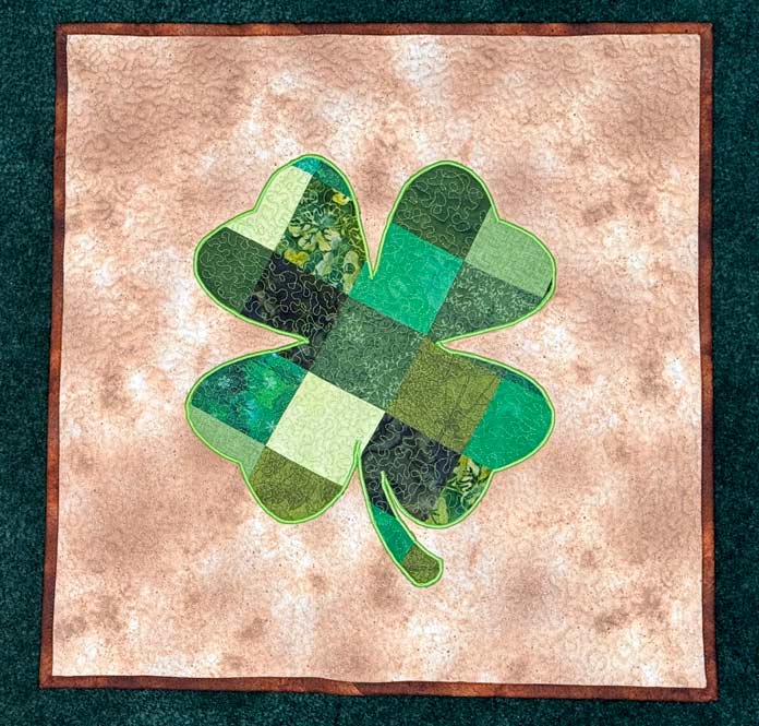 Four-leaf clover quilt made a multicolored green on a cream-colored background
