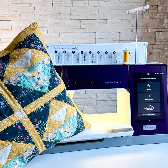 A purple model of the PFAFF creative icon 2 welcome screen and options: Sewing, Embroidery or mySewnet with a finish patchwork block in the hoop cushion