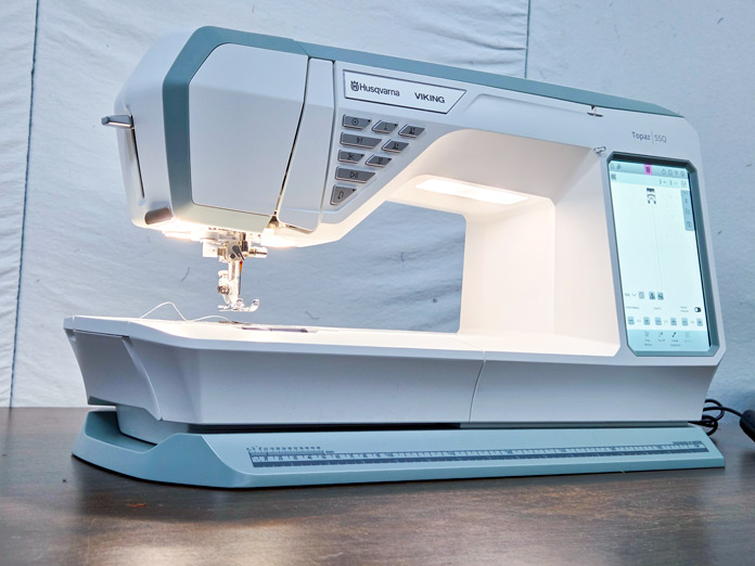 A white sewing machine with a large computer screen