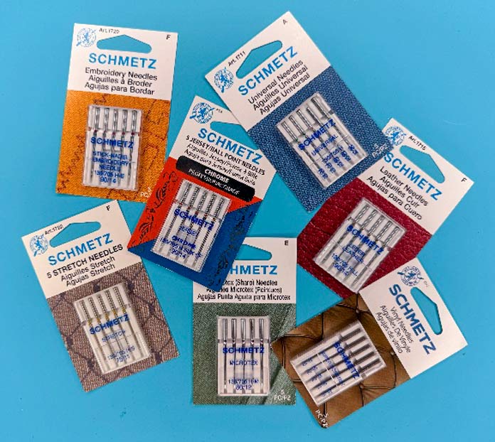Multiple packages of different sewing machine needles and sizes.