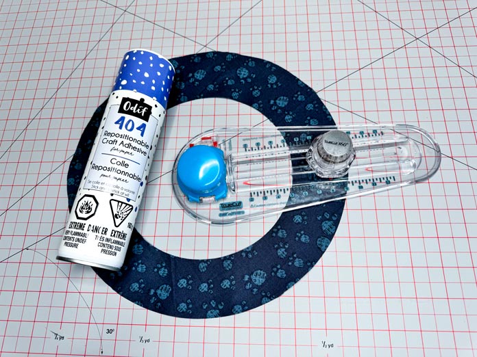 A can of Odif 404 spray and fix permanent repositionable adhesive and a TrueCut 360 Circle Cutter on top of a circle.