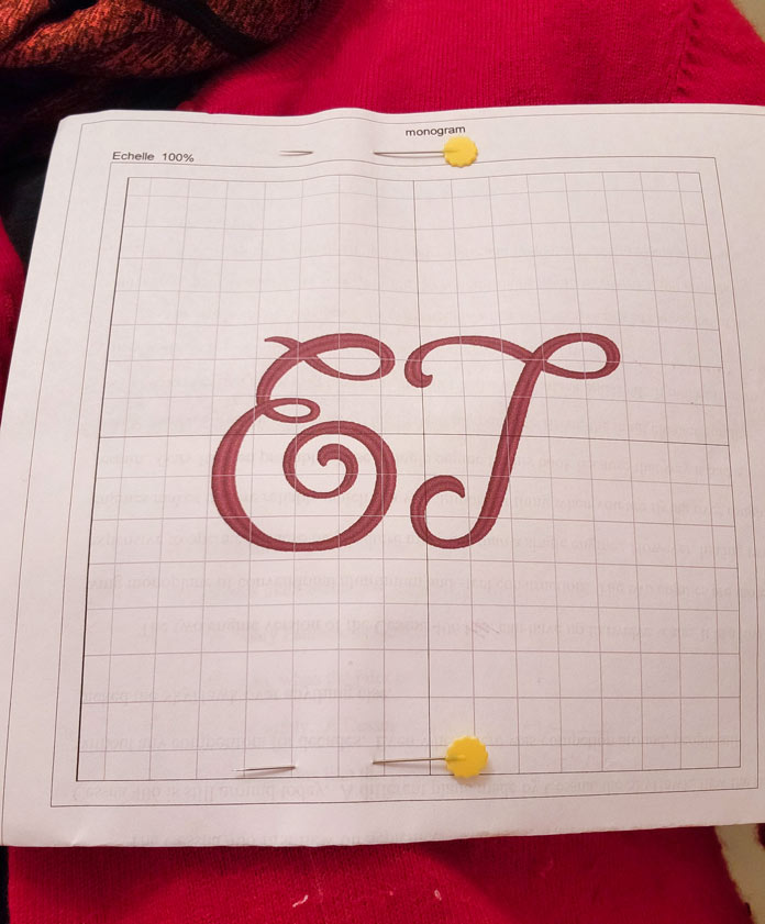 A white paper template with a two-letter monogram pinned on a red sweater