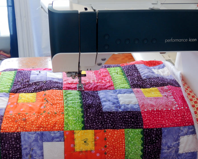 Machine quilting a colorful Modern Blooms wall quilt with the PFAFF performance icon.