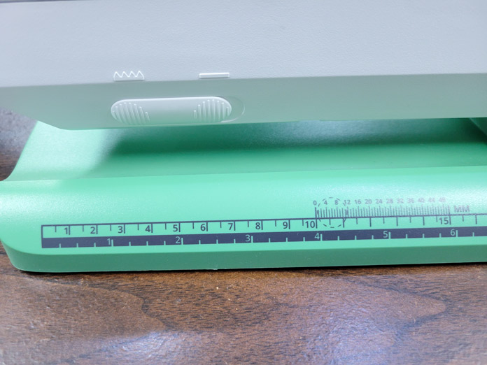 A green base of a sewing machine with a ruler marked in inches and centimeters