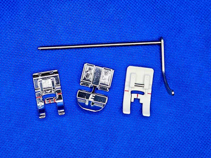 Two metal and one plastic presser feet and a metal bar on a blue background; Husqvarna VIKING ONXY 25