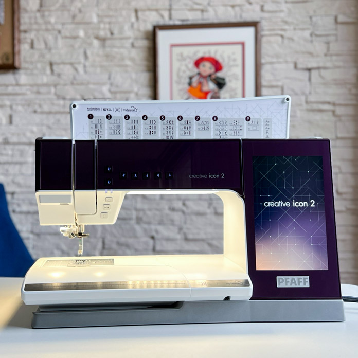 The PFAFF creative icon 2 Sewing and Embroidery Machine with the lights on and the lid open showing the stitch categories