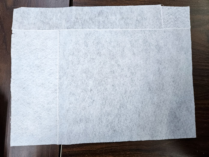 A rectangle made of pieces of white fusible fleece joined with white thread
