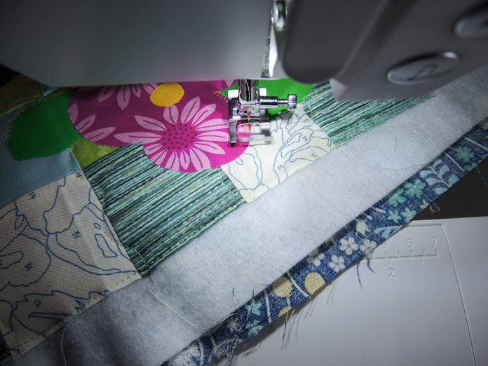 Overhead view of red guide mark on the presser foot lined up on the edge of the flower applique