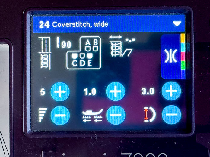 The black computer screen on the purple and white serger, showing the stitch settings for coverstitch wide stitch including a diagram of needle placement; PFAFF admire air 7000