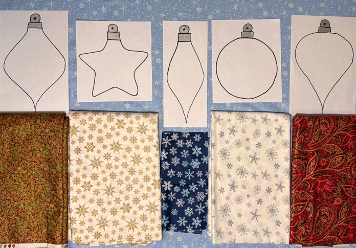 5 ornament templates are matched to different Christmas-themed fabrics. Gütermann Dekor Metallic Thread 200m – Gold, Gütermann Dekor Metallic Thread 200m - Col. 41, Gütermann Dekor Metallic Thread 200m – Red, Gütermann Dekor Metallic Thread 200m - Christmas Green, Gütermann Dekor Metallic Thread 200m - Col. 1005, Gütermann Denim Thread 100m – Black, UNIQUE Baby Rick Rack 3mm x 3.7m – Scarlet, UNIQUE Medium Rick Rack 6mm x 2.3m - Emerald Green, UNIQUE Jumbo Rick Rack 10mm x 2.3m - Metallic Gold, SCHMETZ #1743 Metallic Needles Carded - 80/12 - 5 count, SCHMETZ #1752 Metallic Needles Carded - 90/14 - 5 count, LDH 8½“ Craft Scissors – Purple, HeatnBond Lite Iron-On Adhesive - 43cm x 30m (17″ x 32 ¾yds) bolt, HeatnBond Stitch n Sew Tear-Away Stabilizer - 50.8cm x 22.8m (20″ x 25yds), oliso M3Pro Project Iron – Coral, OLFA 45mm RTY-2/DX/MAG Ergonomic Rotary Cutter – Magenta, UNIQUE Quilting Wool Pressing Mat - 18″ x 24″ - Grey