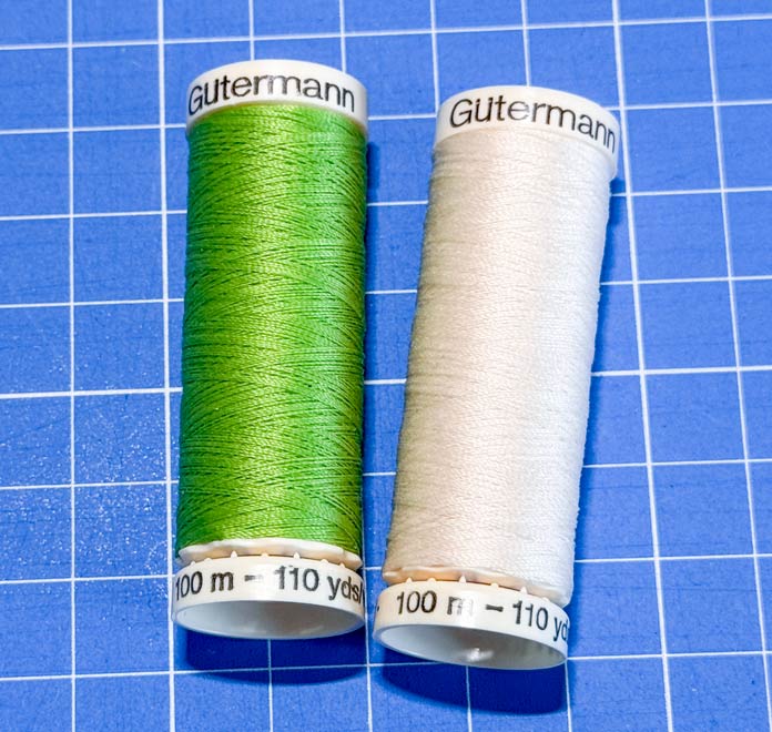 A spool of green and crem colored Gütermann threads.