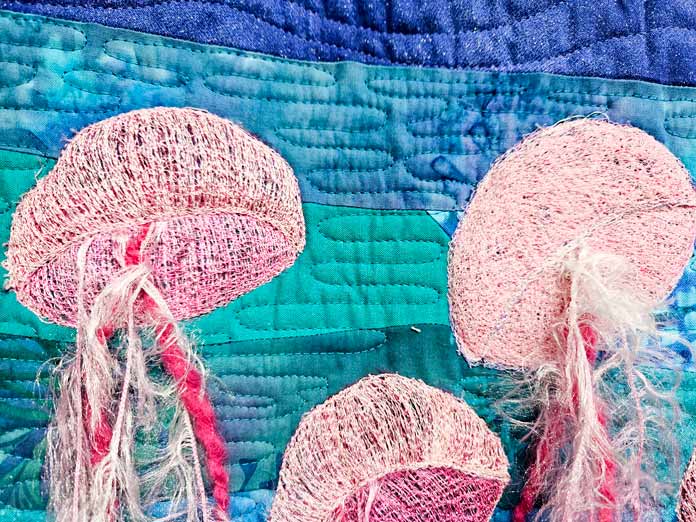 Jellyfish using a pink thread on blue fabric