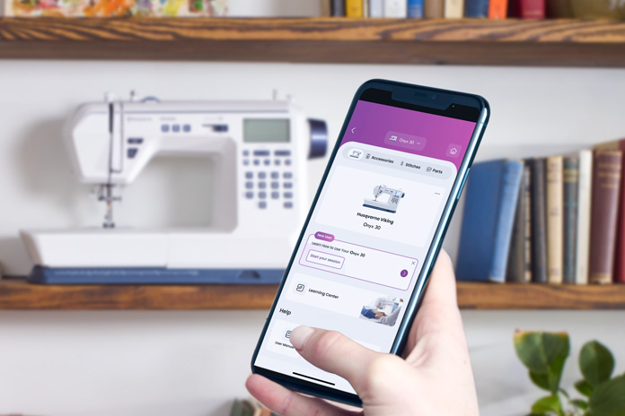 A smartphone in front of a white sewing machine